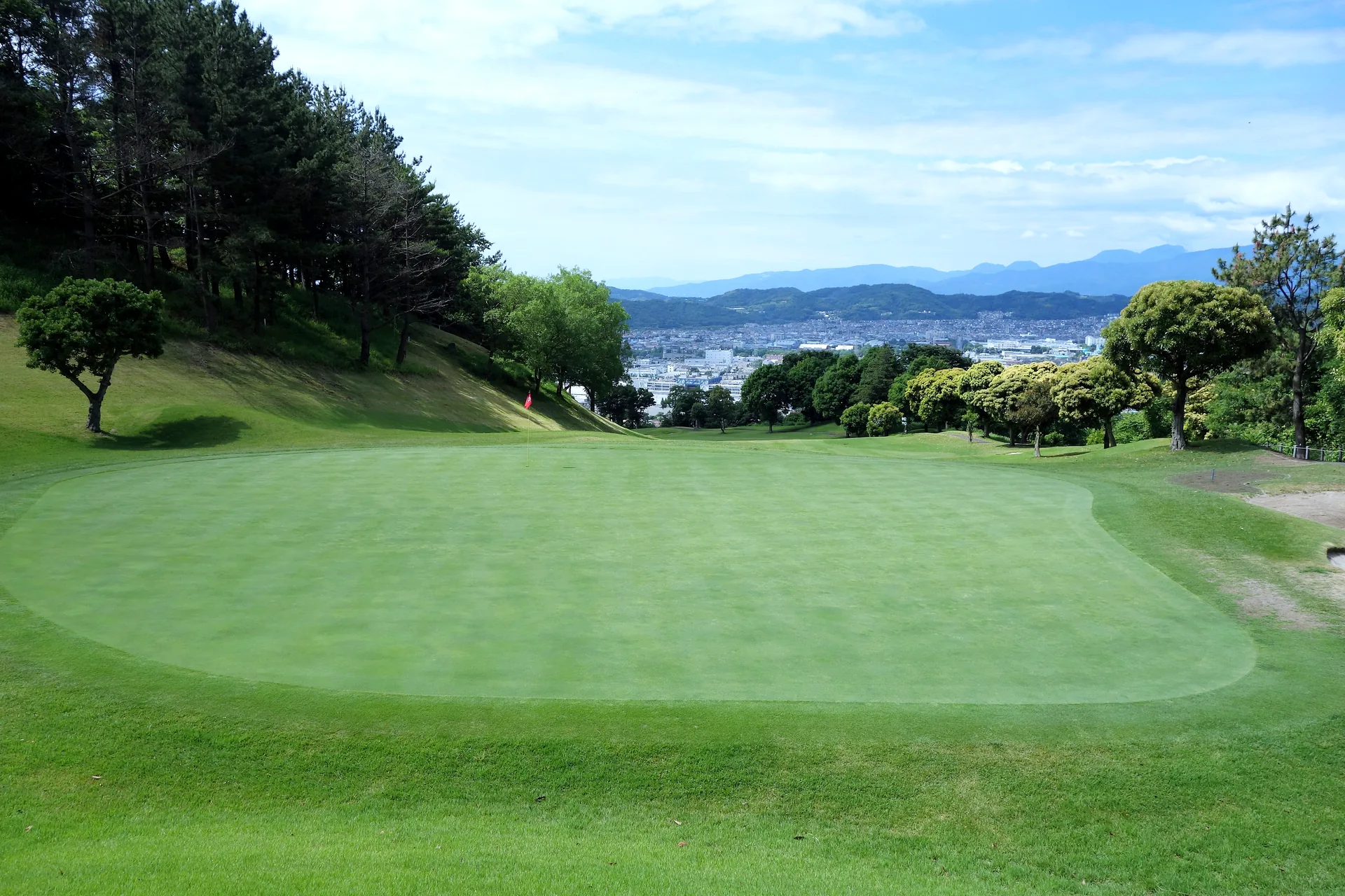 グリーン側から見た最終18番ホール。奥に秦野市街と丹沢の山並み。